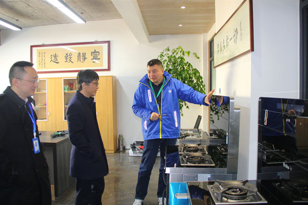 焦点娱乐电器副总裁王春雷为沈建新教授一行人介绍焦点娱乐·AIoT智能集成灶